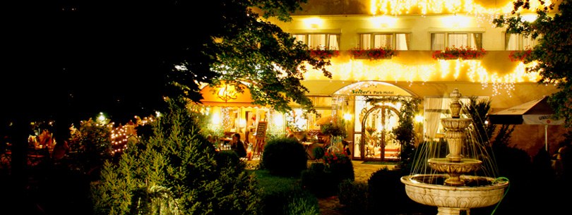 Seibel's Park-Hotel am Abend: beleuchtete Fassade, Gartenterrasse und Brunnen